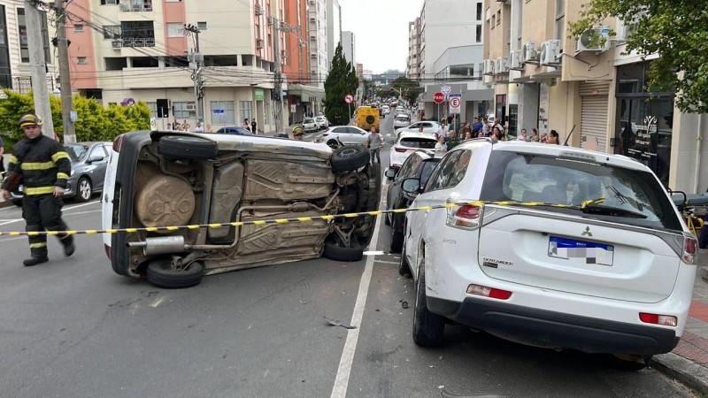 Carro dos Correios bate em veículo estacionado e tomba no Centro de Criciúma 