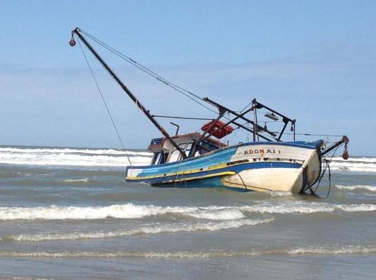 Barco pesqueiro encalha na praia, no Balneário Torneiro